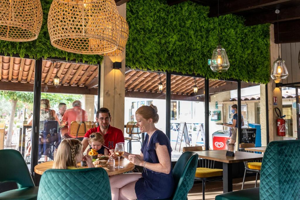 une femme et un enfant assis à une table dans un restaurant dans l'établissement Camping RCN Domaine de la Noguière, au Muy