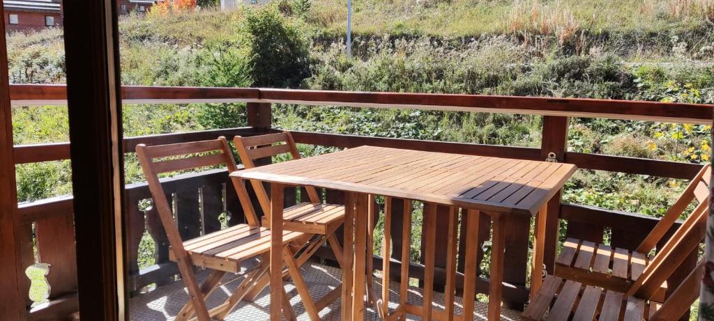 une table en bois et deux chaises sur un balcon dans l'établissement Residence la Dame Blanche, à Puy-Saint-Vincent 16 autres photos