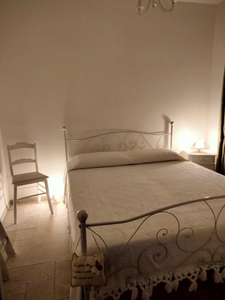 une chambre avec un lit blanc et une chaise dans l'établissement Le Casette fra le Masserie, à Fasano