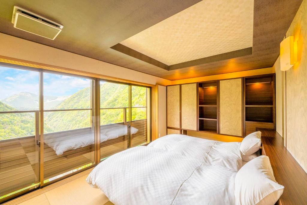 une chambre avec un lit et une grande fenêtre dans l'établissement Iya Onsen, à Miyoshi