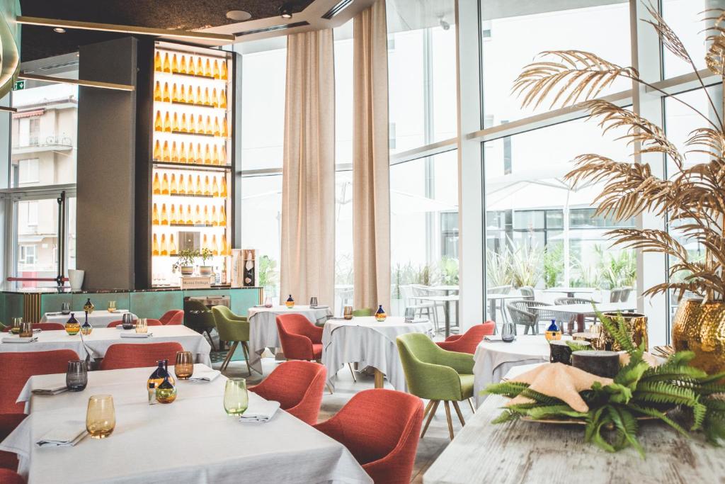 un restaurant avec des tables et des chaises et de grandes fenêtres dans l'établissement J44 Lifestyle Hotel, à Lido di Jesolo