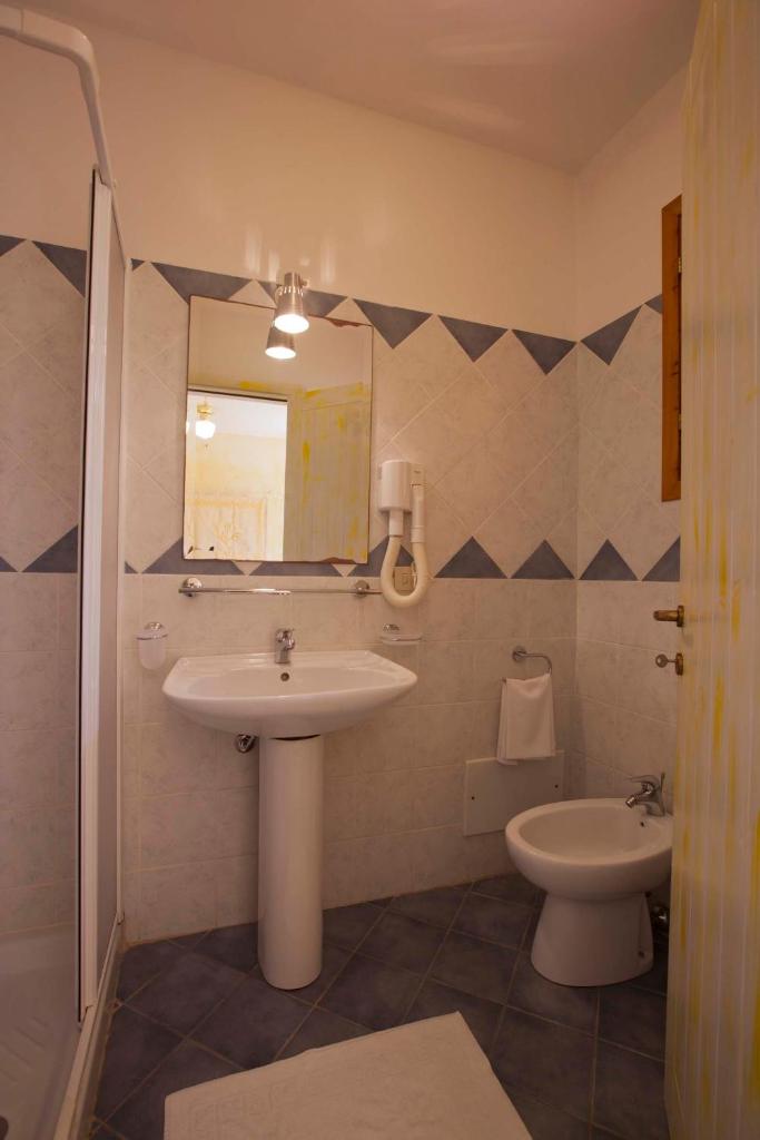 une salle de bain avec un lavabo, des toilettes et un miroir dans l'établissement Club Esse Shardana, à Santa Teresa Gallura 49 autres photos