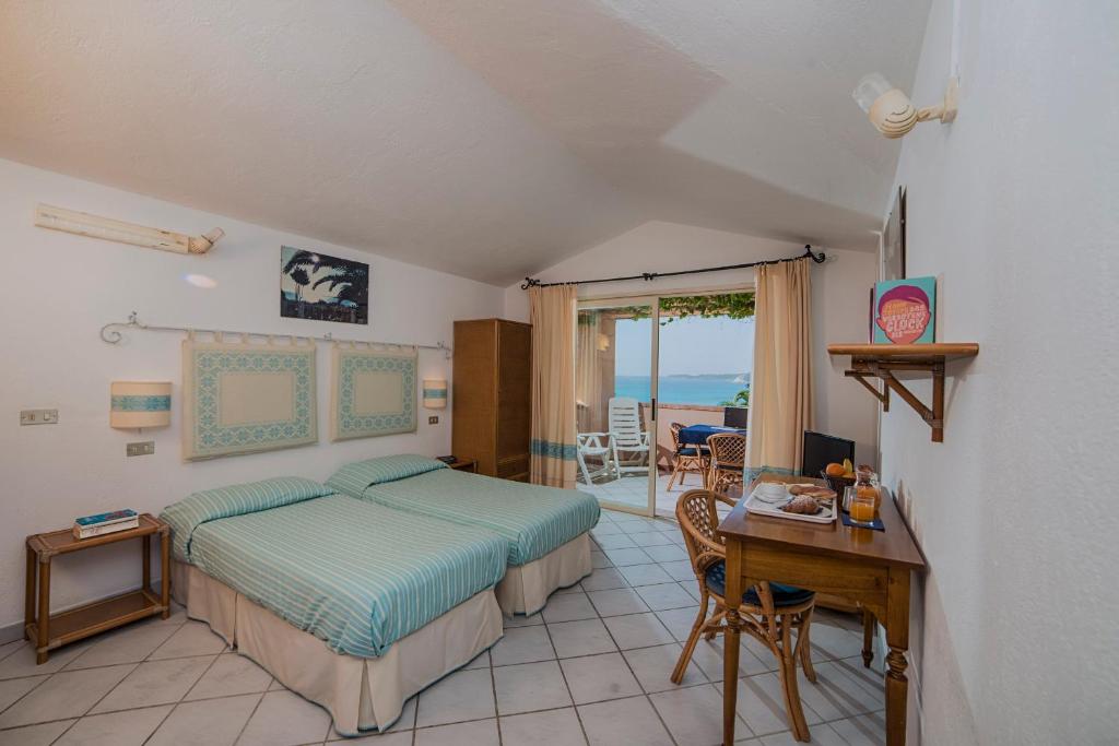 - une chambre avec un lit, un bureau, une table et des chaises dans l'établissement Residence Fenicia, à Villasimius