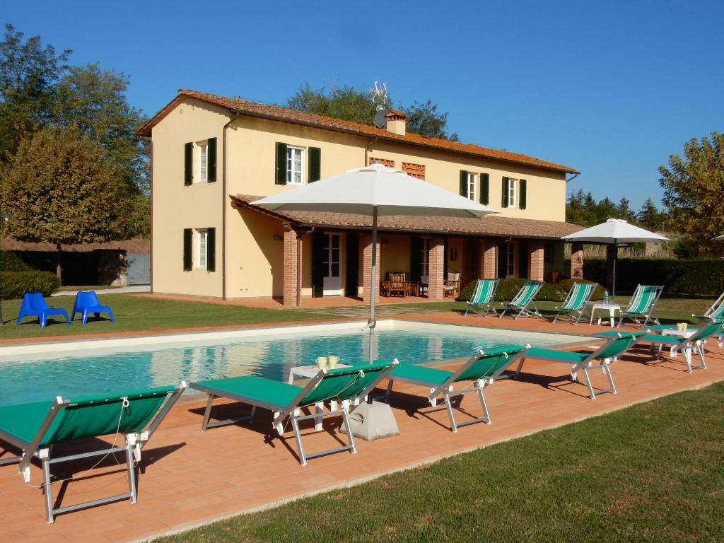une piscine avec des chaises et un parasol à côté d'une maison dans l'établissement Villa Le Farfalle, à Castelvecchio