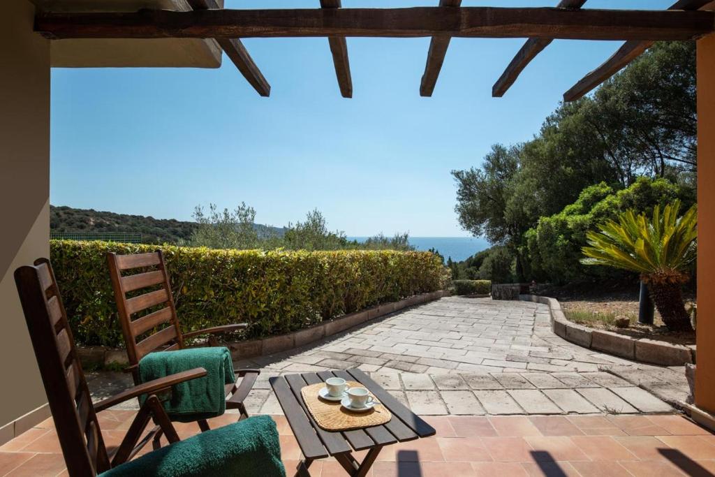 d'une terrasse avec des chaises et une table offrant une vue. dans l'établissement Eco Village Baia Delle Ginestre, à Teulada 67 autres photos