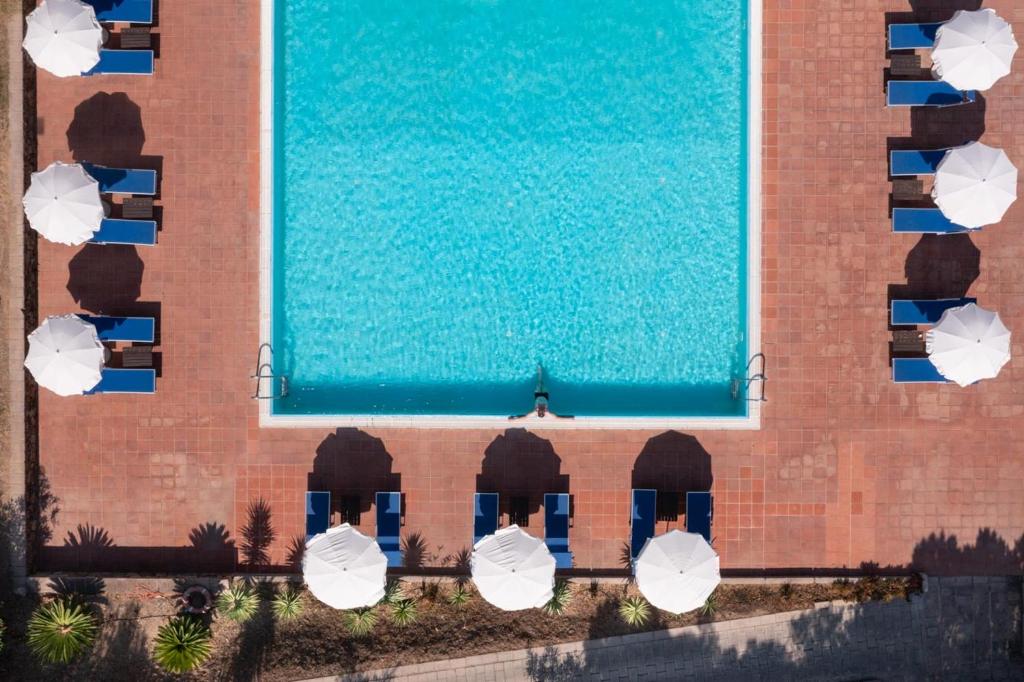 une vue aérienne d'une piscine avec des parasols dans l'établissement Eco Village Baia Delle Ginestre, à Teulada