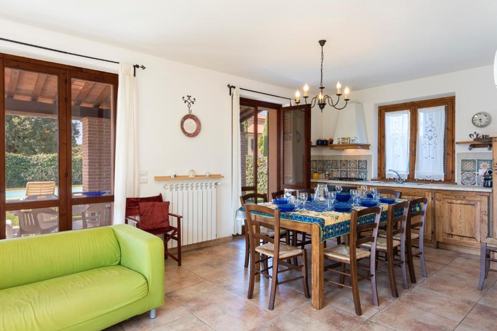 une salle à manger avec une table et un canapé vert dans l'établissement Villa Clemente by Mmega, à Lucignano