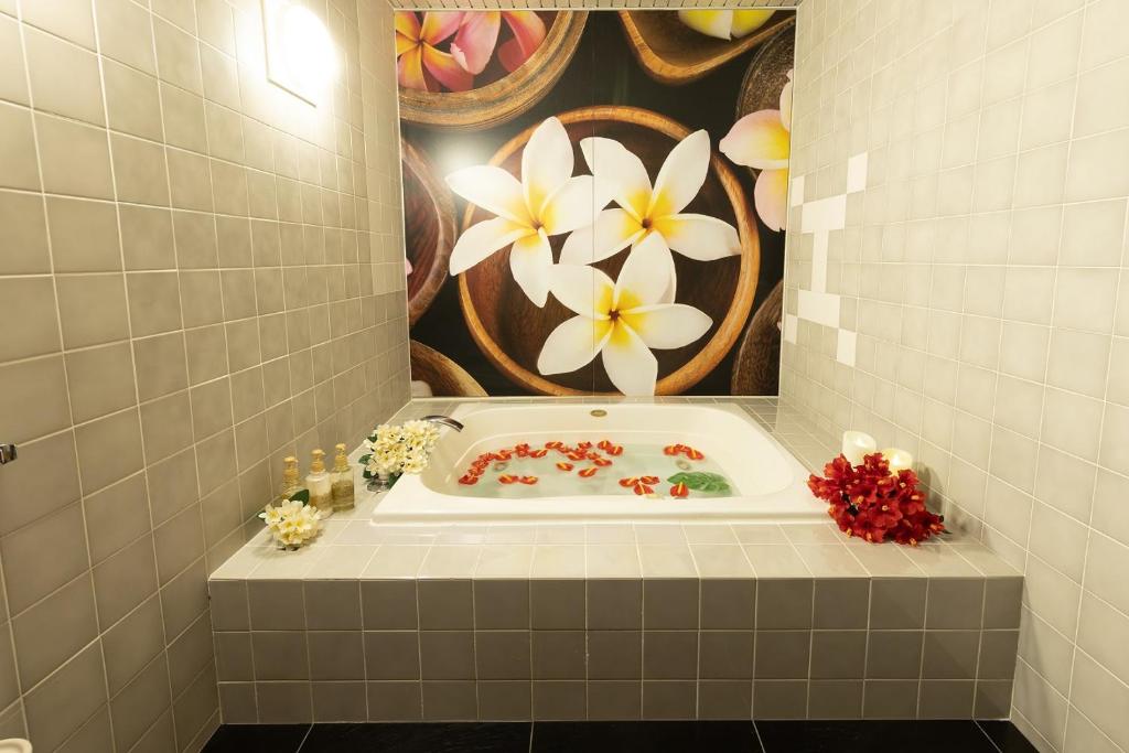 La salle de bains est pourvue d'une baignoire et de fleurs sur le mur. dans l'établissement ホテル チャペルココナッツ 亀山, à Kameyama 42 autres photos