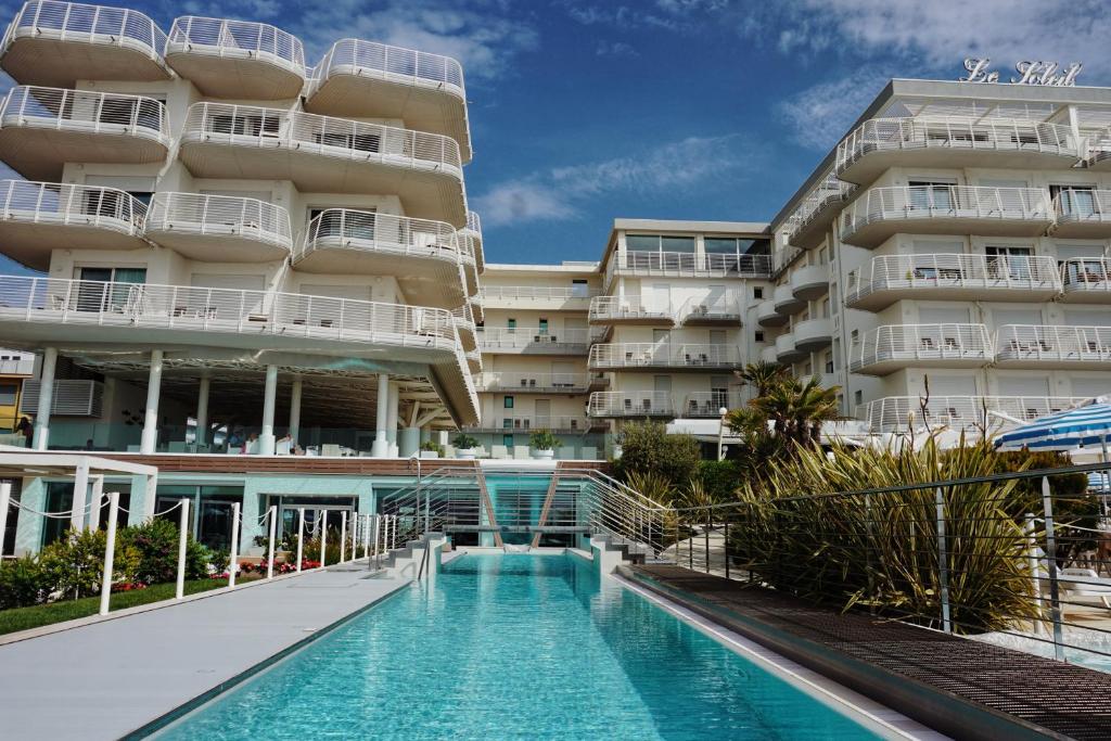 un hôtel avec une piscine devant un bâtiment dans l'établissement Hotel Le Soleil, à Lido di Jesolo