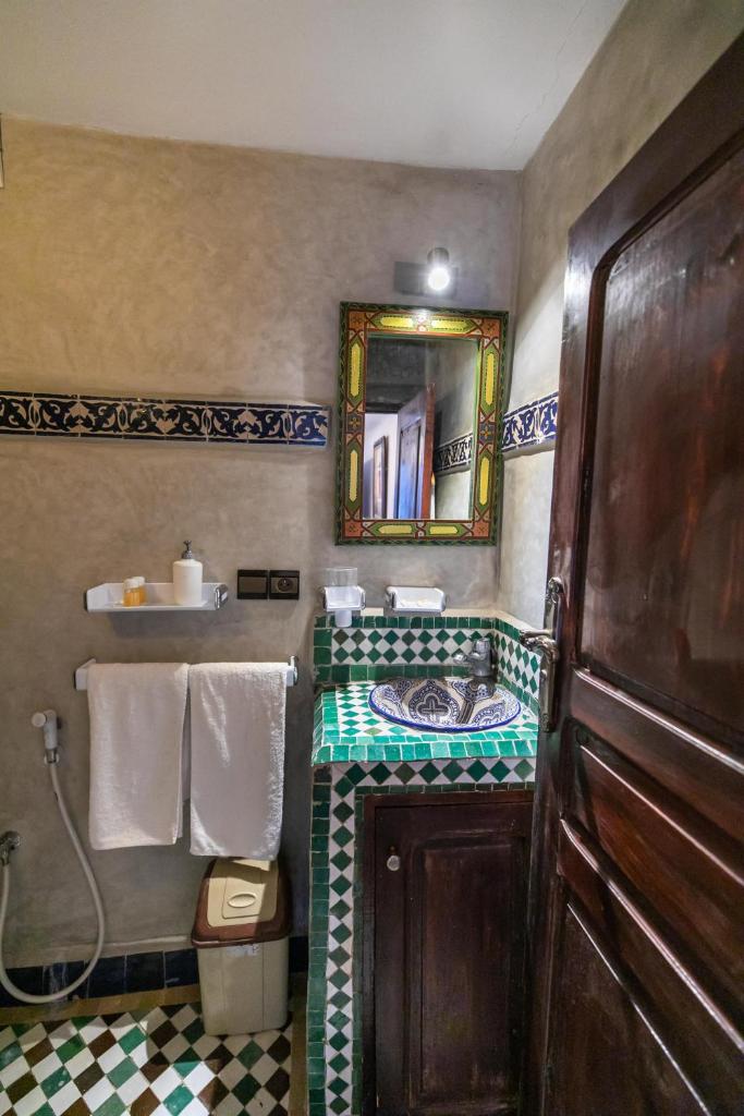 une salle de bain avec un lavabo, un miroir et des serviettes dans l'établissement Riad Dar Chrifa, à Fès 37 autres photos