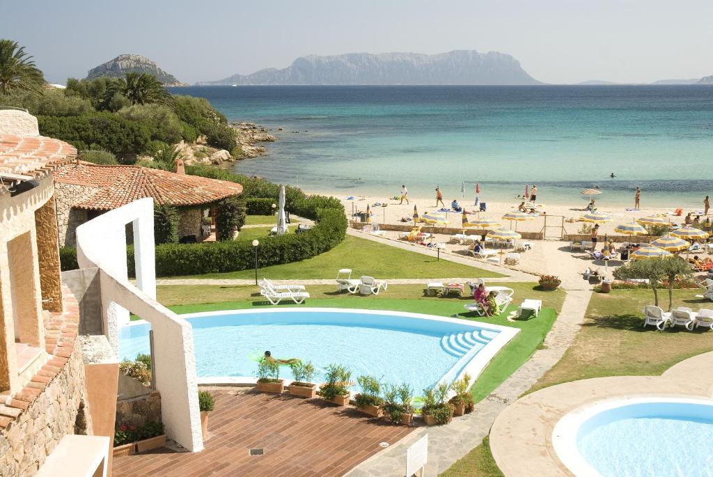 - une vue sur la plage depuis un complexe doté d'une piscine dans l'établissement Hotel Resort & Spa Baia Caddinas, à Golfo Aranci