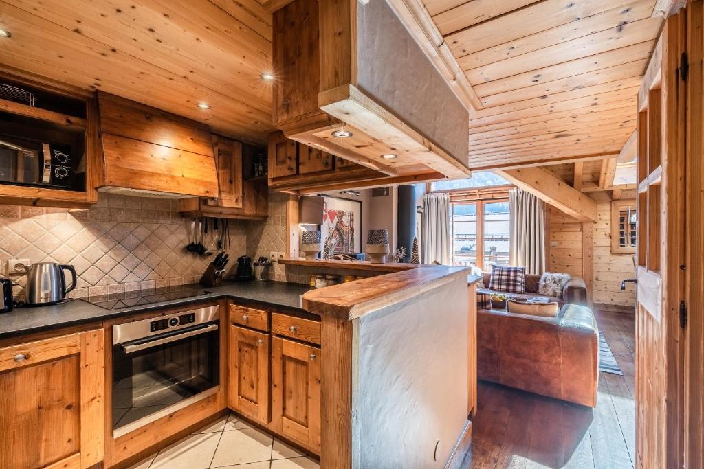 une cuisine avec des armoires en bois et un four à plaques de cuisson dans l'établissement Apartment Garapa Morzine - by EMERALD STAY, à Morzine