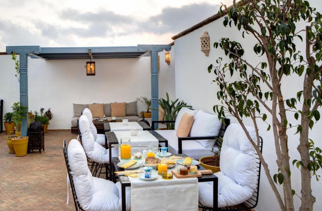 une terrasse avec des chaises blanches, des tables, de la nourriture et du jus d'orange. dans l'établissement Riad Amaris, à Rabat 37 autres photos