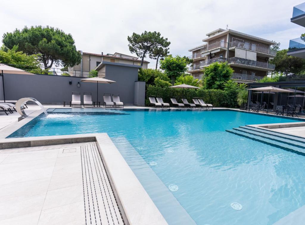 une piscine avec des chaises et un bâtiment dans l'établissement Coast Hotel & Spa - Adults Only Aperto tutto l'anno, à Milano Marittima