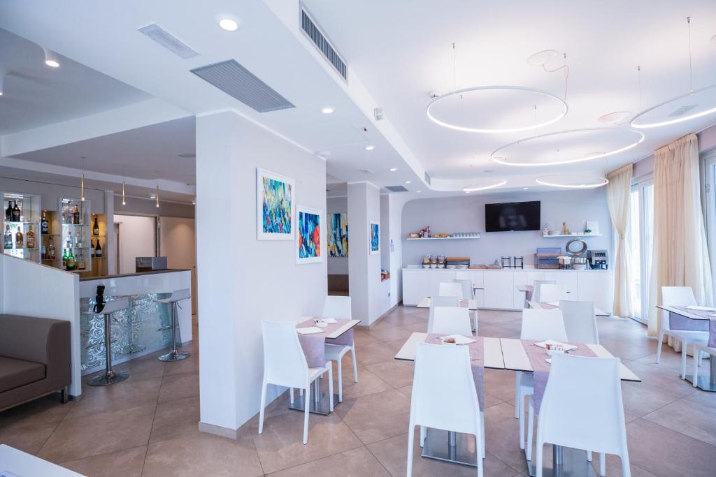 une salle à manger avec des tables blanches et des chaises blanches dans l'établissement Hotel Baby, à Rimini
