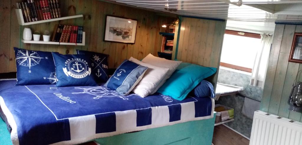 une chambre avec un lit avec des oreillers bleus et blancs dans l'établissement PENICHE ONDINE, à Plombières-lès-Dijon