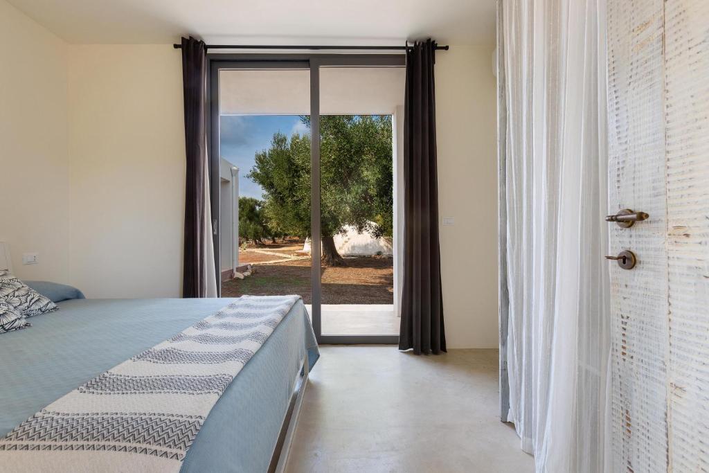 une chambre avec un lit et une porte coulissante en verre dans l'établissement Villa Magali' by Perle di Puglia, à Specchiolla