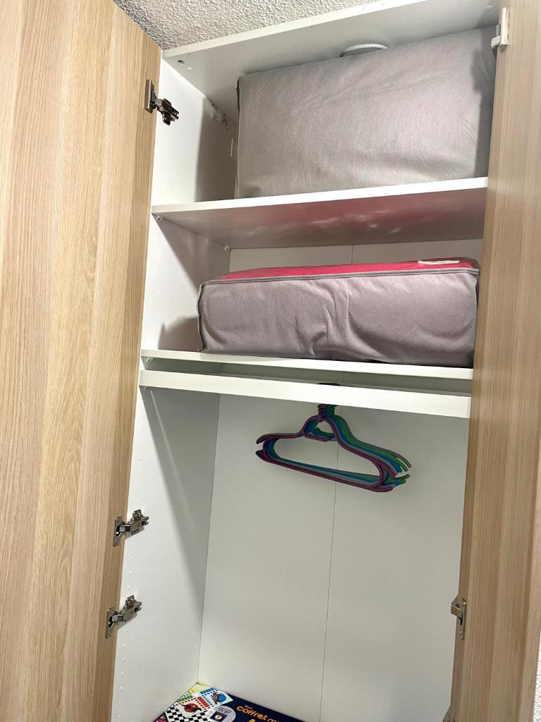 - un placard avec quelques étagères, un oreiller et une serviette dans l'établissement L'AnsloBoys Montagne L2, à Les Deux Alpes