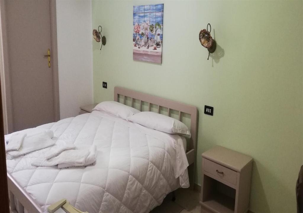 un lit avec des draps blancs et des oreillers dans une chambre dans l'établissement Ahm7nani, à Mascali