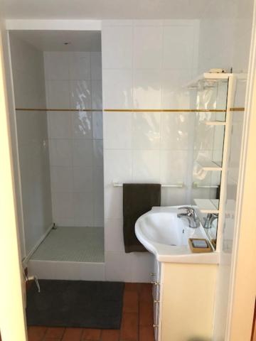 une salle de bain blanche avec un lavabo et une douche dans l'établissement Gite du Moulin de la Virvée, à Saint-André-de-Cubzac