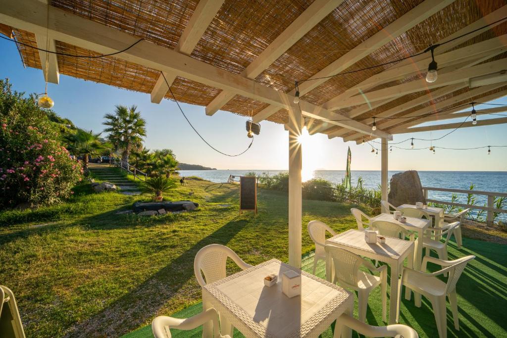 une terrasse avec des tables et des chaises et l'océan dans l'établissement Hotel Santa Lucia, à Parghelia