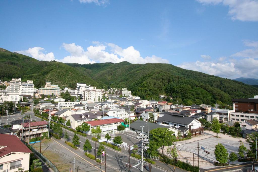 une ville avec des bâtiments et des montagnes en arrière-plan dans l'établissement Sakaenoyu Ryokan, à Matsumoto