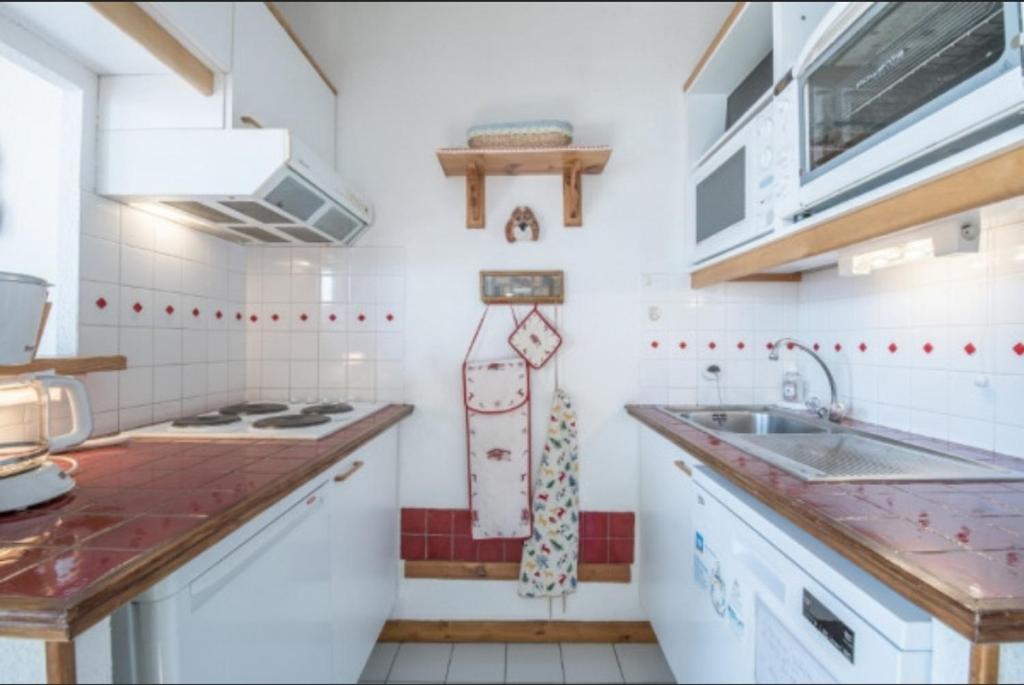 une cuisine blanche avec un évier et une cuisinière dans l'établissement Résidence Saboia Courchevel La Tania - Belle Vue, à Courchevel 14 autres photos