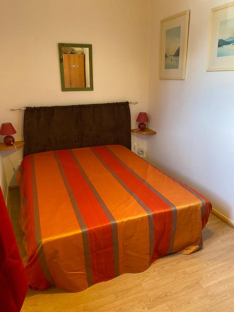 - une chambre avec un lit et une couverture rayée orange dans l'établissement Les Myrtilles Pyrénées 2000, à Bolquère-Pyrénées 2000