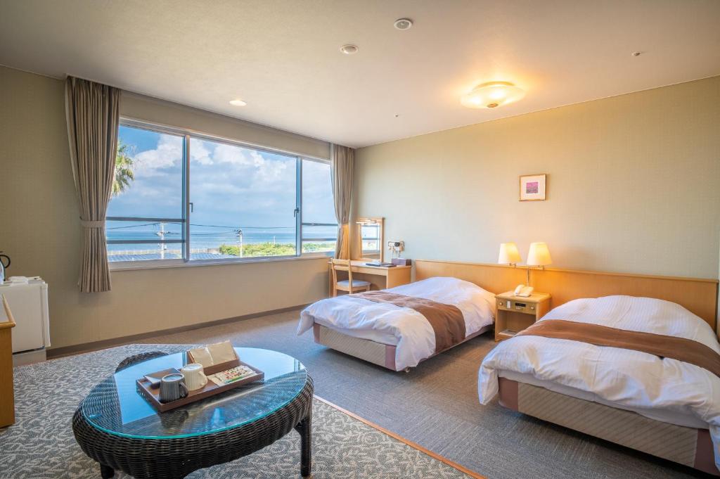 une chambre d'hôtel avec deux lits et une grande fenêtre dans l'établissement Koran no Yu Kinkouro, à Ibusuki
