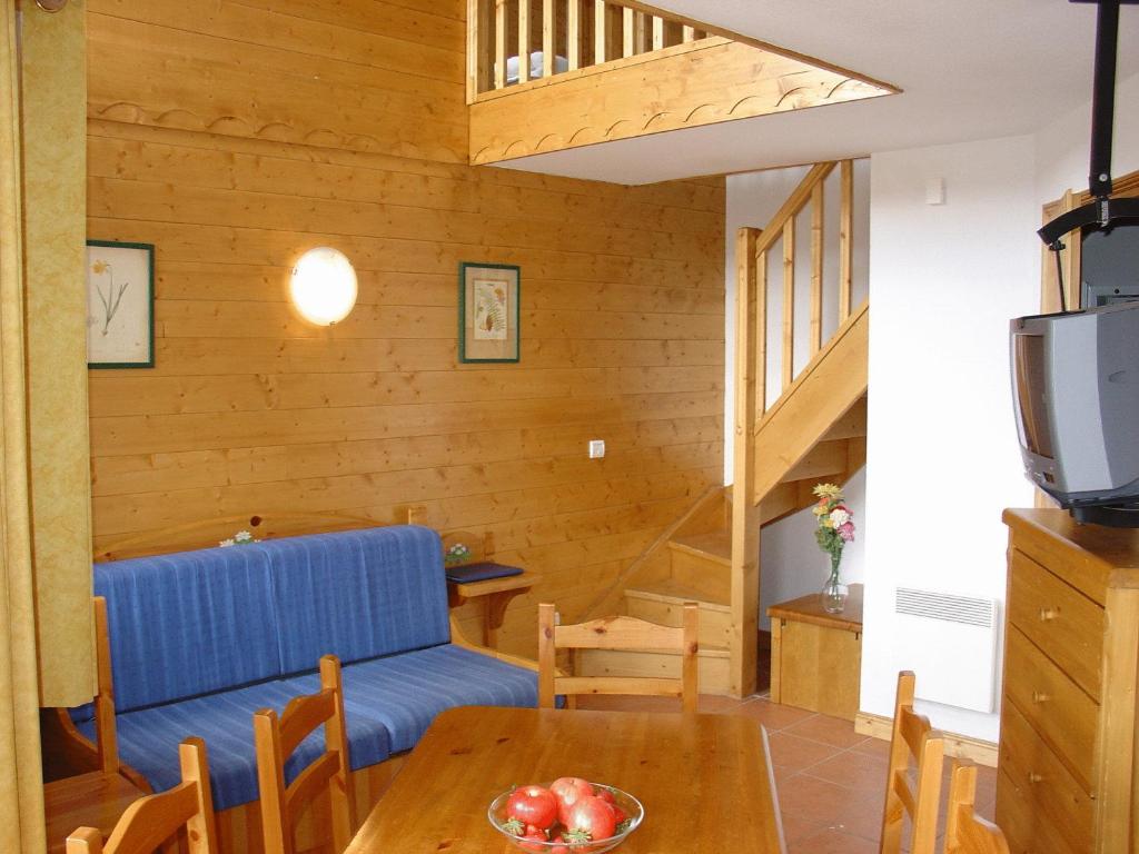 un salon avec un canapé bleu et une table dans l'établissement Madame Vacances Lodges des Alpages, à La Plagne