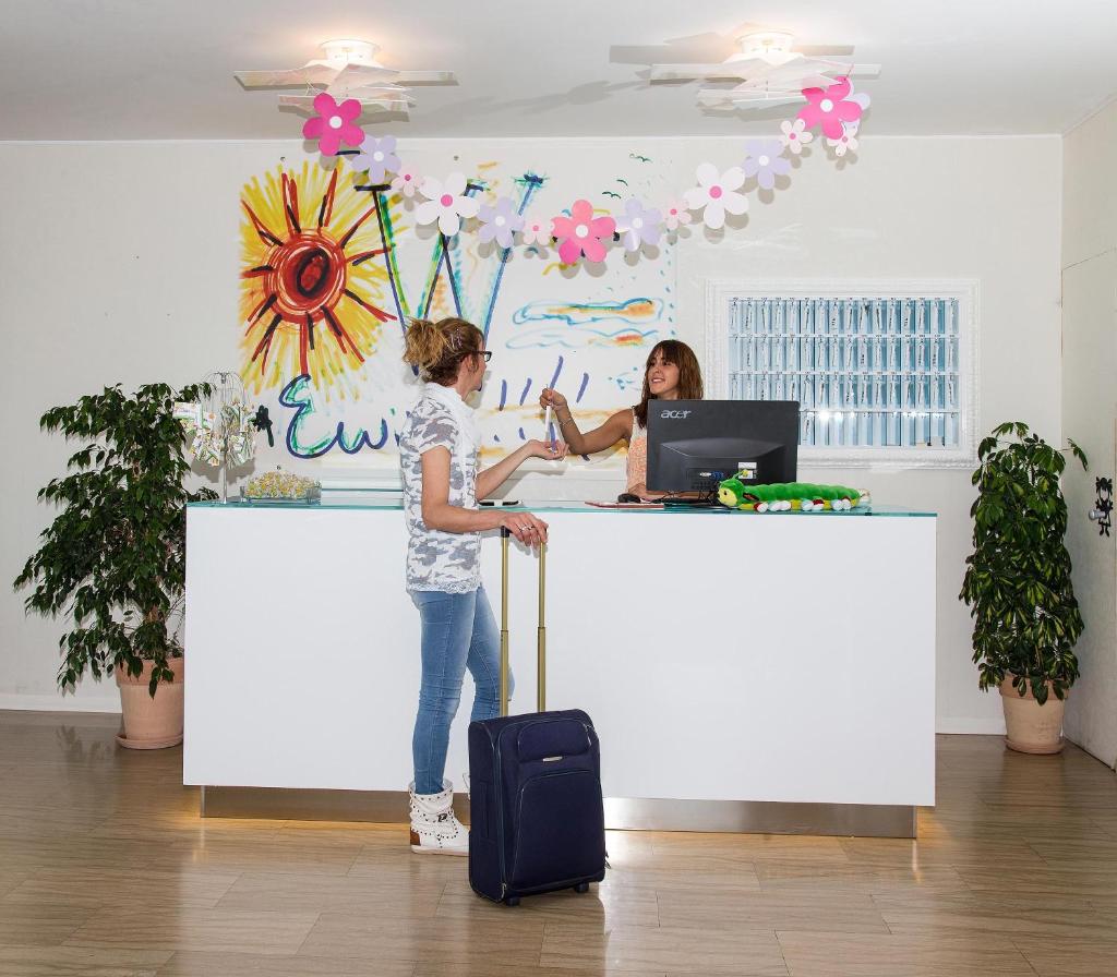 deux femmes debout à un comptoir avec une valise dans l'établissement Hotel Adelphi, à Riccione 36 autres photos