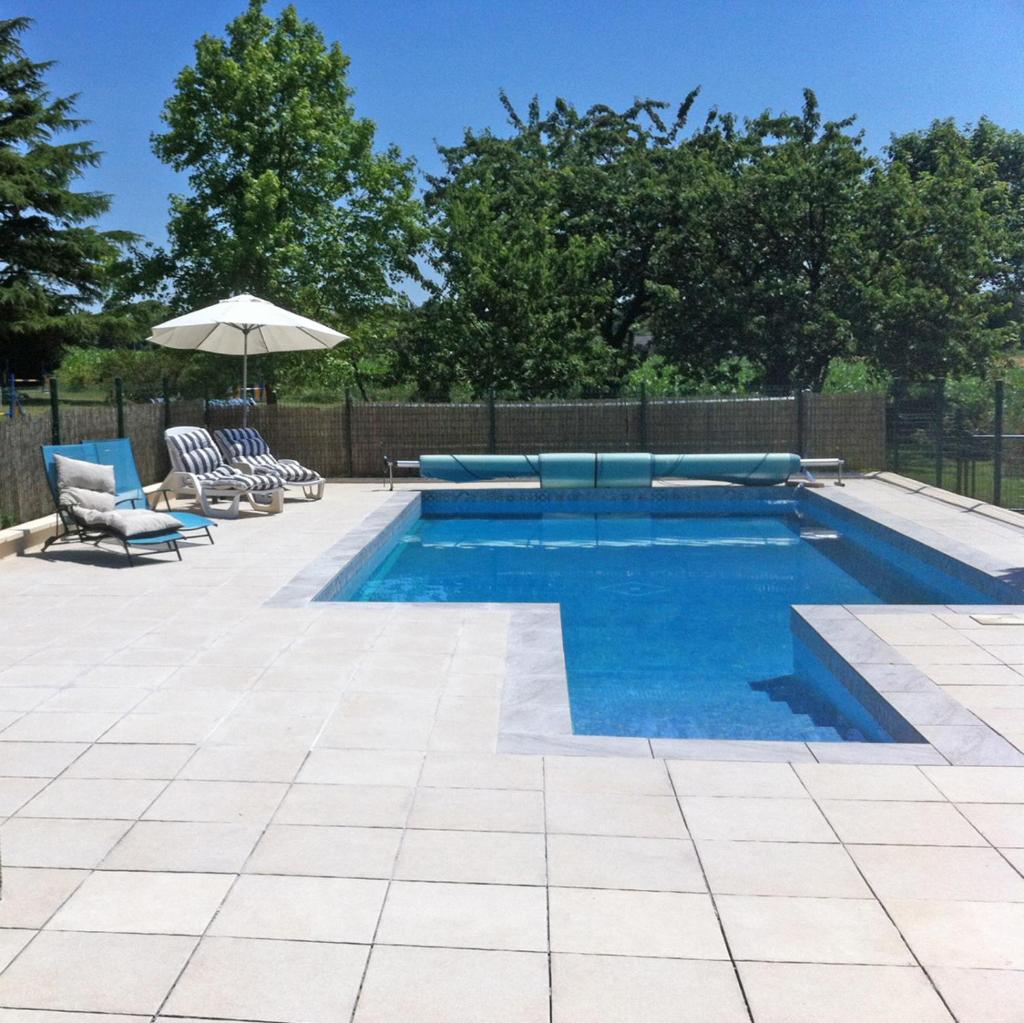 une piscine avec des chaises et un parasol dans l'établissement Les Maricotais Gîte La Crécerelle, à Trévérien