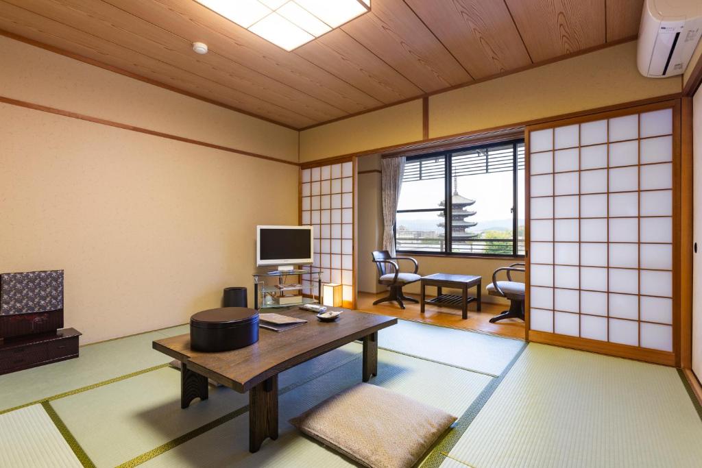 un salon japonais avec une table et une télévision dans l'établissement Kyoto Higashiyamaso, à Kyoto