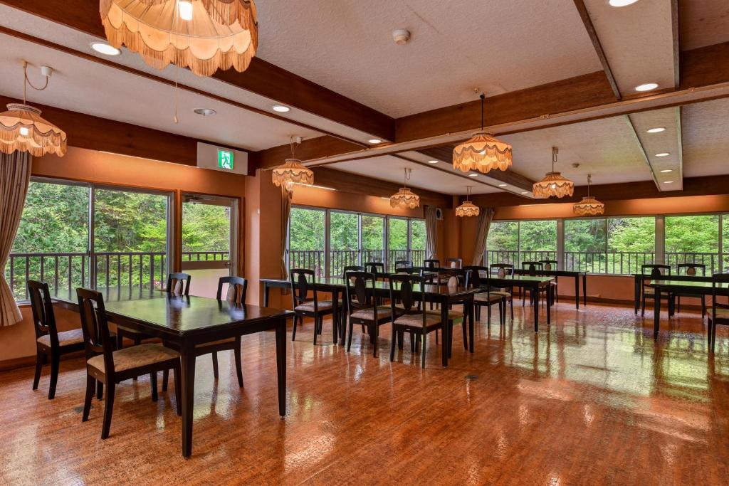 une salle à manger avec tables, chaises et fenêtres dans l'établissement Yama no Yado Meiji Onsen, à Chino