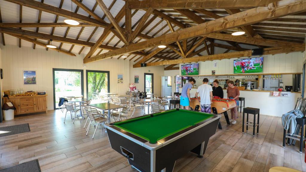 Cette chambre comprend un billard, des tables et des chaises. dans l'établissement CAMPING AZU'RIVAGE, à Azur