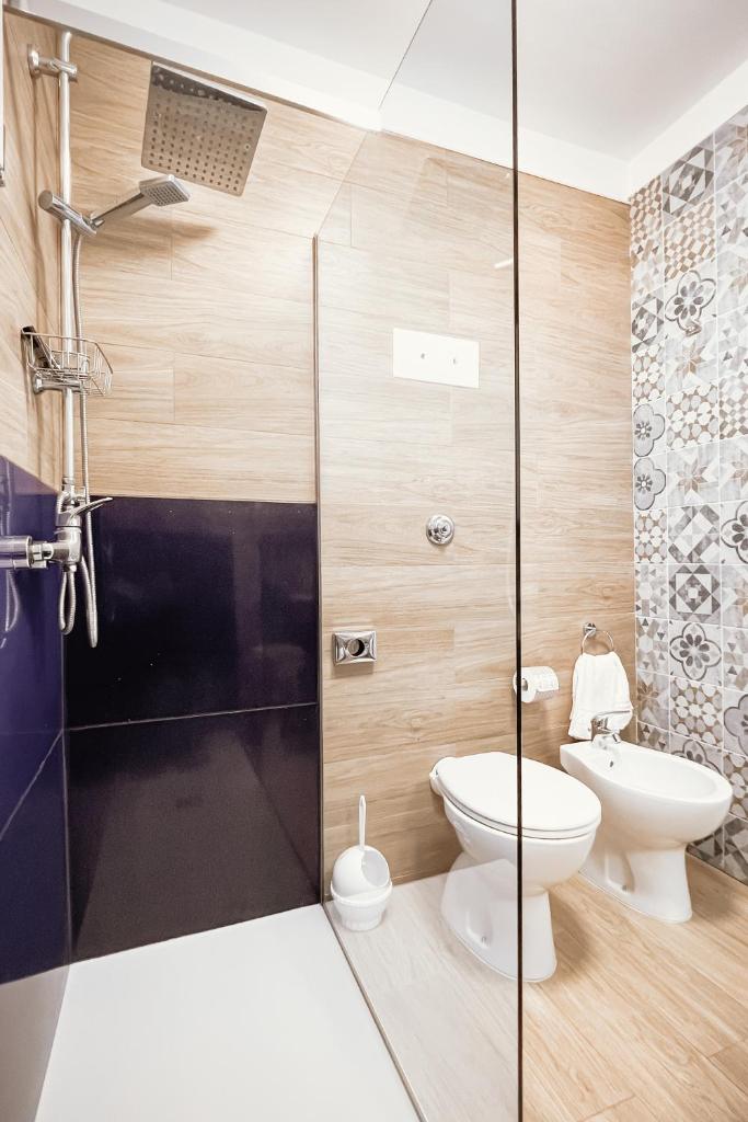 une salle de bain avec toilettes et douche en verre dans l'établissement Hotel Blue Marine, à Lignano Sabbiadoro