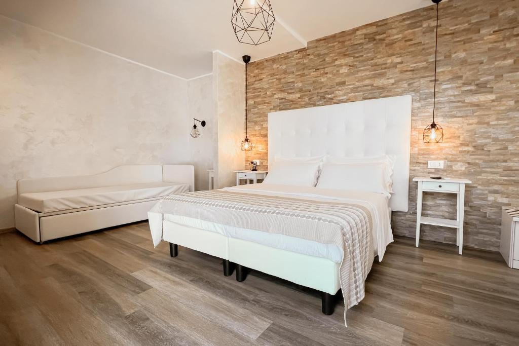 une chambre avec un lit blanc et un mur de briques dans l'établissement Hotel Blue Marine, à Lignano Sabbiadoro