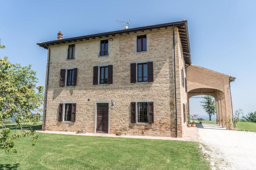 une vue extérieure sur un bâtiment en briques avec une arche dans l'établissement Villa Ca de Poi - Tabiano Castle Country Villas, à Salsomaggiore Terme