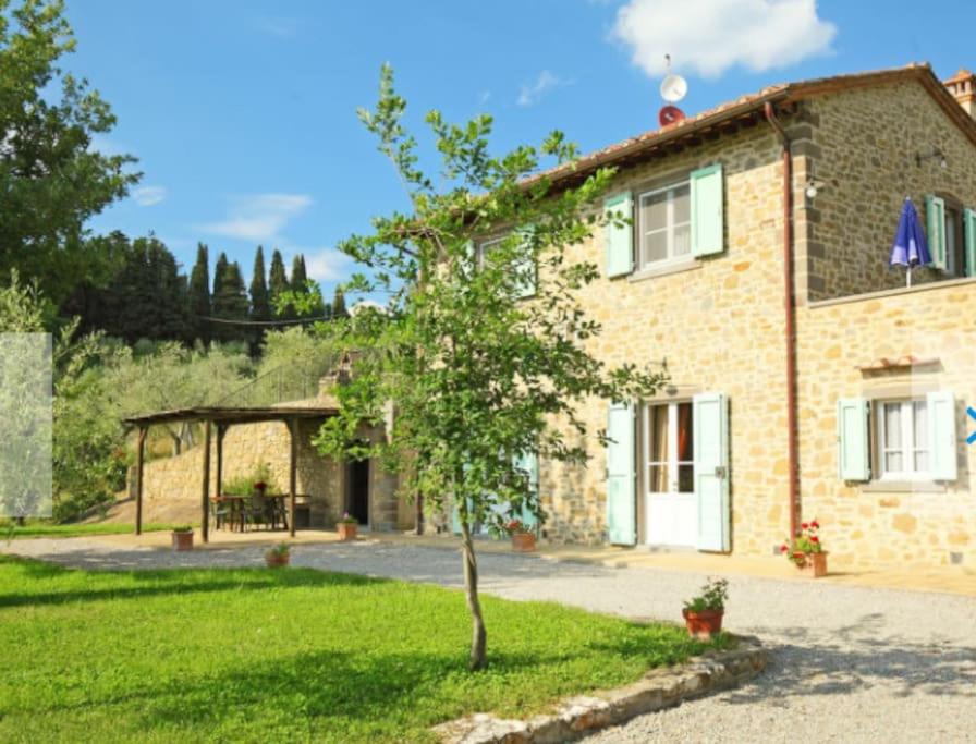 une maison en pierre avec un arbre dans la cour dans l'établissement VILLA PONENTE, à Cortone