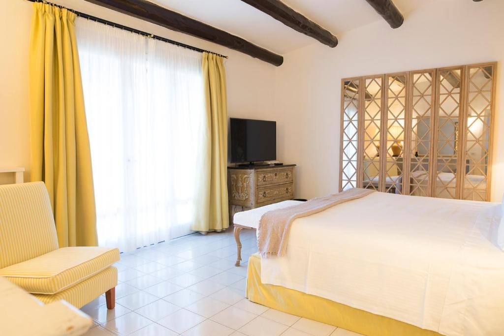 une chambre avec un lit, une télévision et une chaise dans l'établissement Il Pellicano, à Porto Ercole