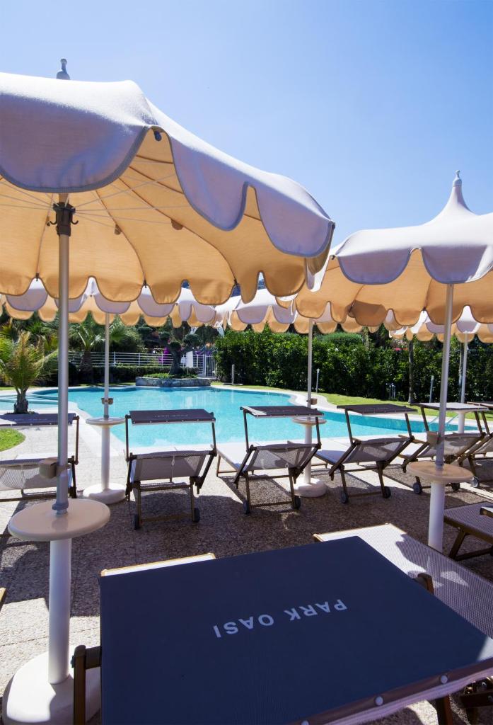 un groupe de chaises et de parasols à côté d'une piscine dans l'établissement Park Oasi Resort, à Zambrone