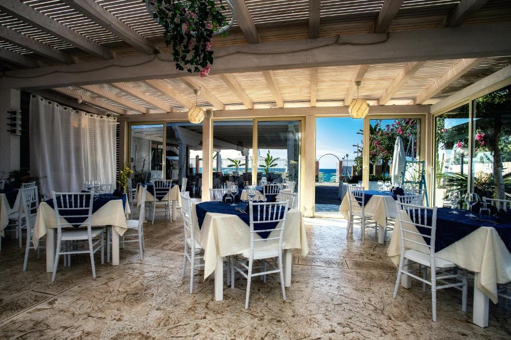 une salle à manger avec des tables bleues et des chaises blanches dans l'établissement Park Oasi Resort, à Zambrone
