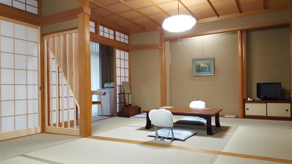 Cette chambre comprend une table et une chaise. dans l'établissement Tsukimotoya Ryokan, à Toyooka