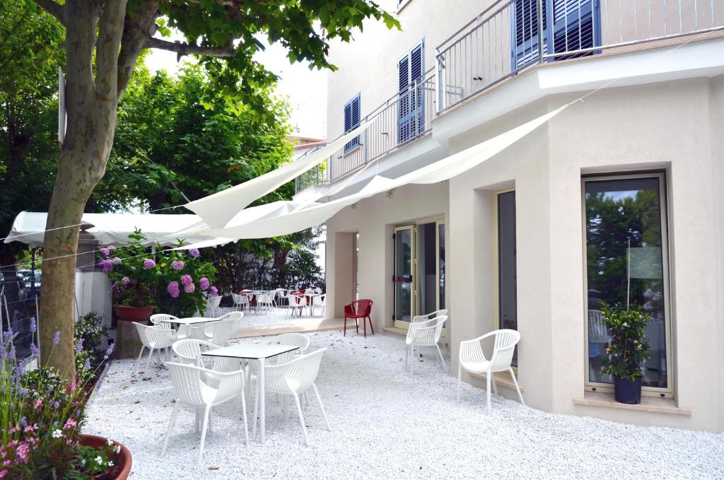 un patio avec des chaises et des tables blanches et un bâtiment dans l'établissement Petit Hotel, à Lido di Camaiore