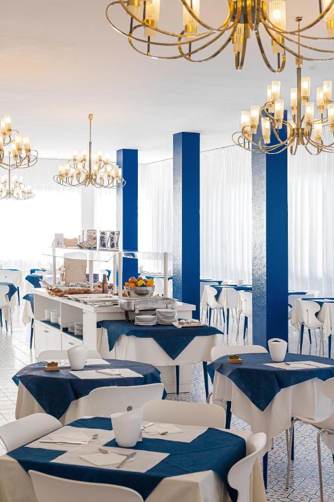 un restaurant avec des tables et des chaises bleues et blanches dans l'établissement Hotel City, à Milano Marittima
