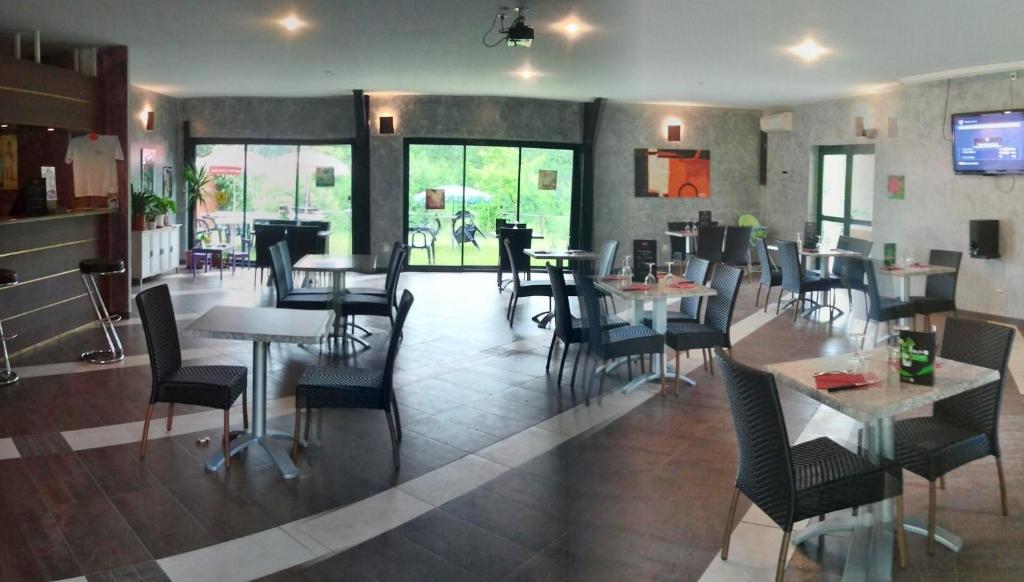 une salle à manger avec des tables et des chaises dans un restaurant dans l'établissement Le Verdoyant, à Thenon