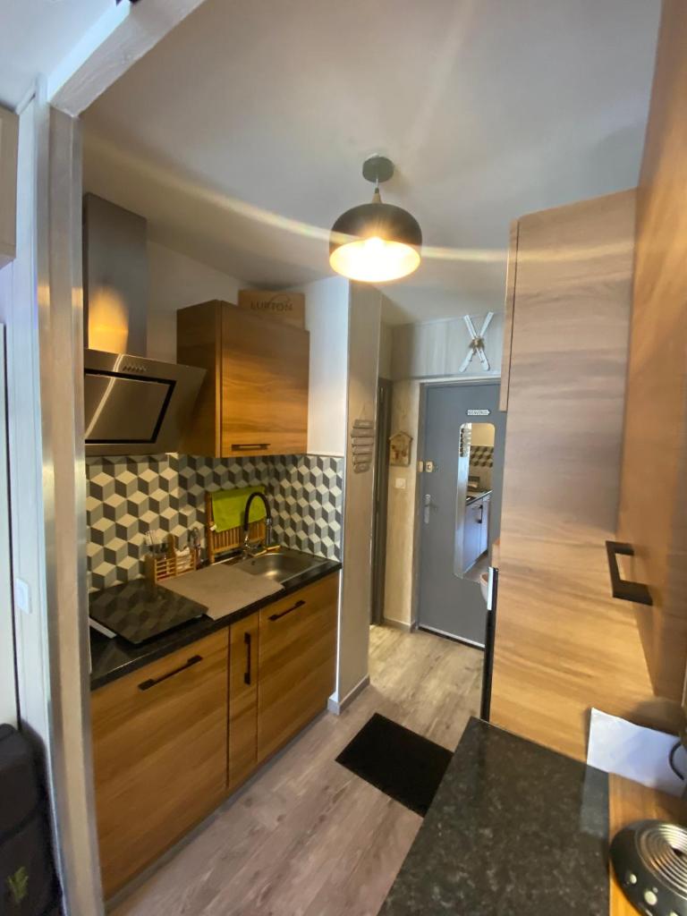 une cuisine avec des armoires en bois et un évier dans l'établissement STUDIO COCOONING SUPERDEVOLUY PIED DES PISTES, à Saint-Étienne-en-Dévoluy