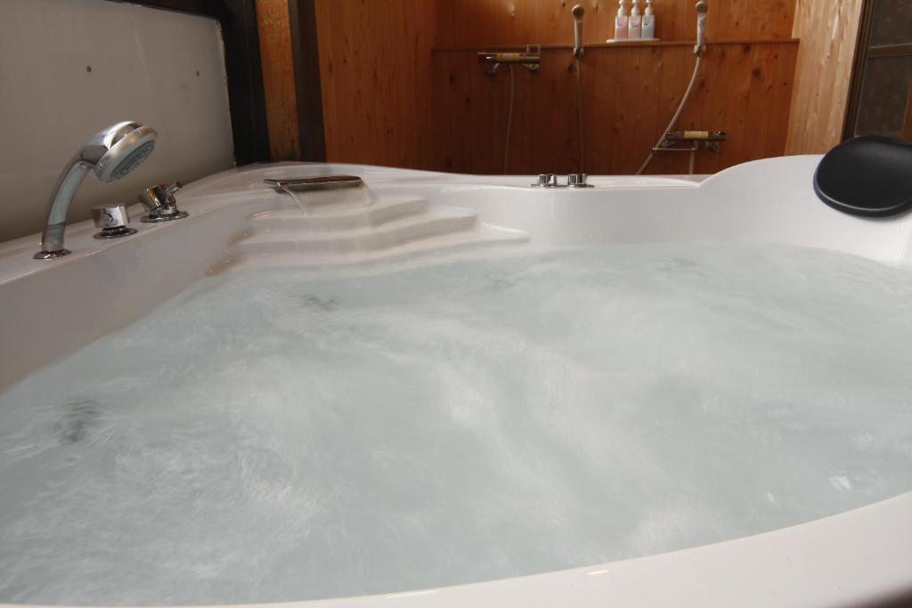 La salle de bains est pourvue d'une baignoire remplie d'eau. dans l'établissement Tsuki no Shizuka, à Matsumoto