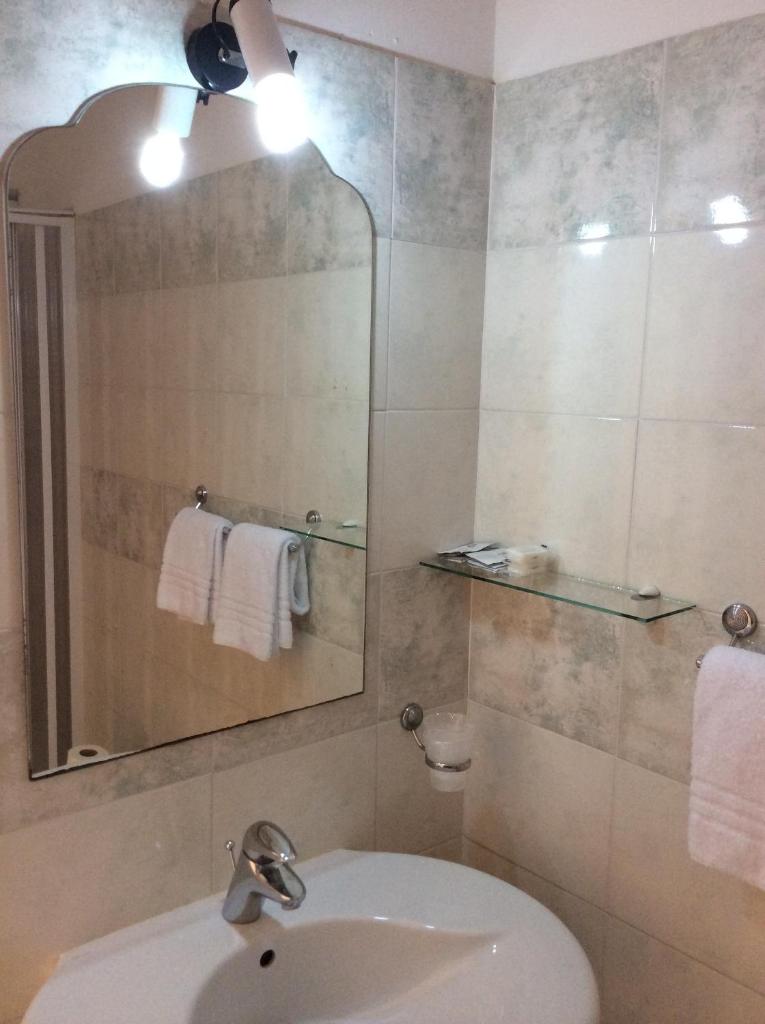 une salle de bain avec un lavabo et un miroir dans l'établissement Hotel San Marco, à Alghero