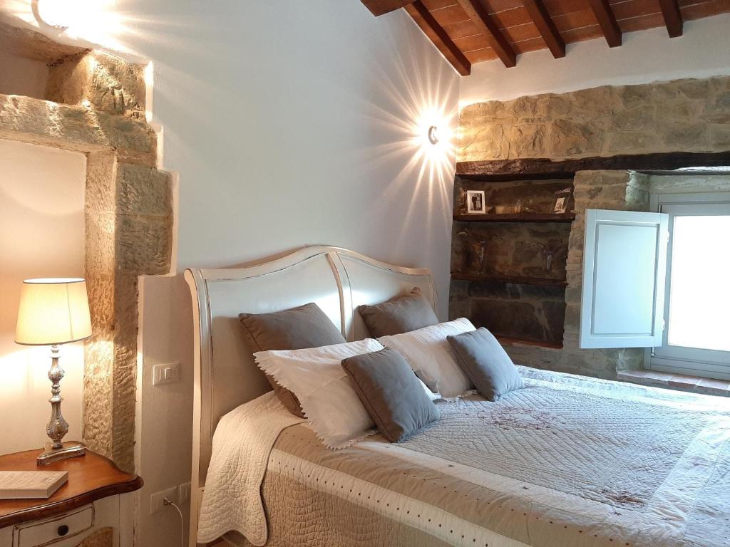 - une chambre avec un lit blanc et un mur en pierre dans l'établissement Villa Galearpe with private pool in Tuscany, à Salutio
